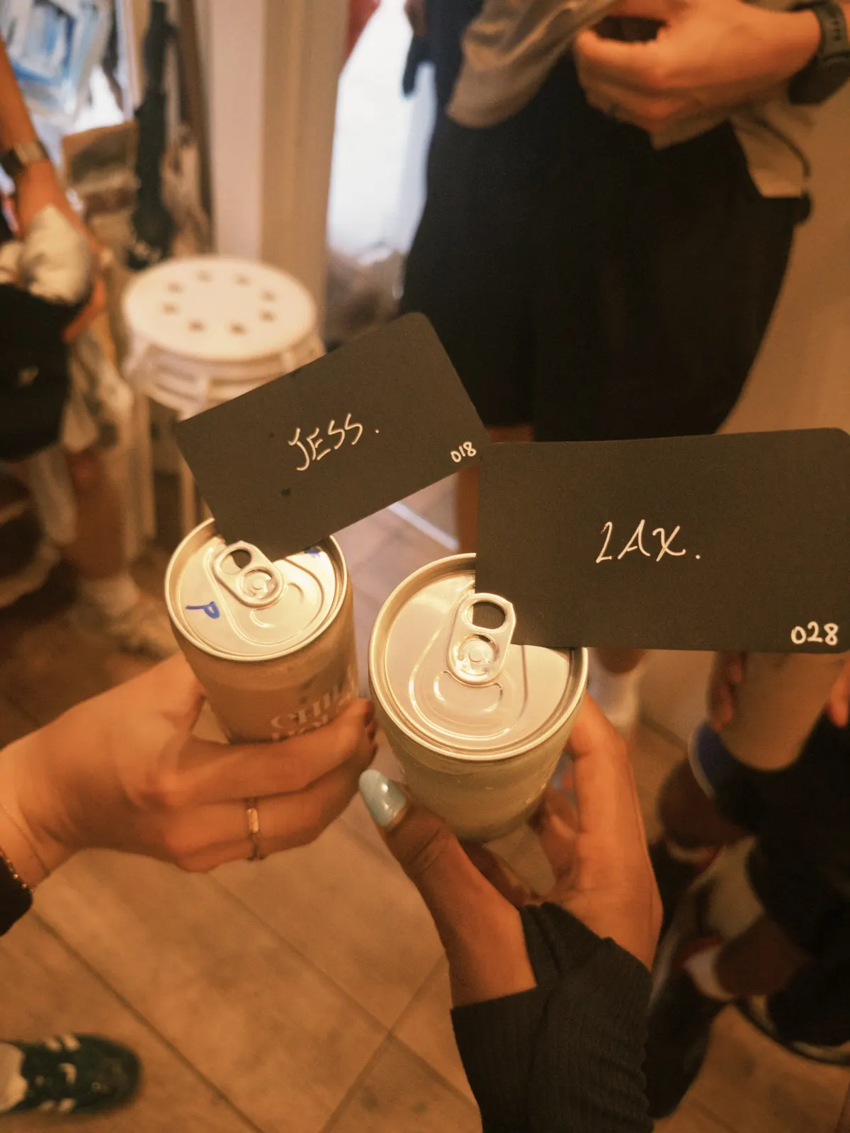 Two cans with handwritten name cards tucked under the ring pulls
