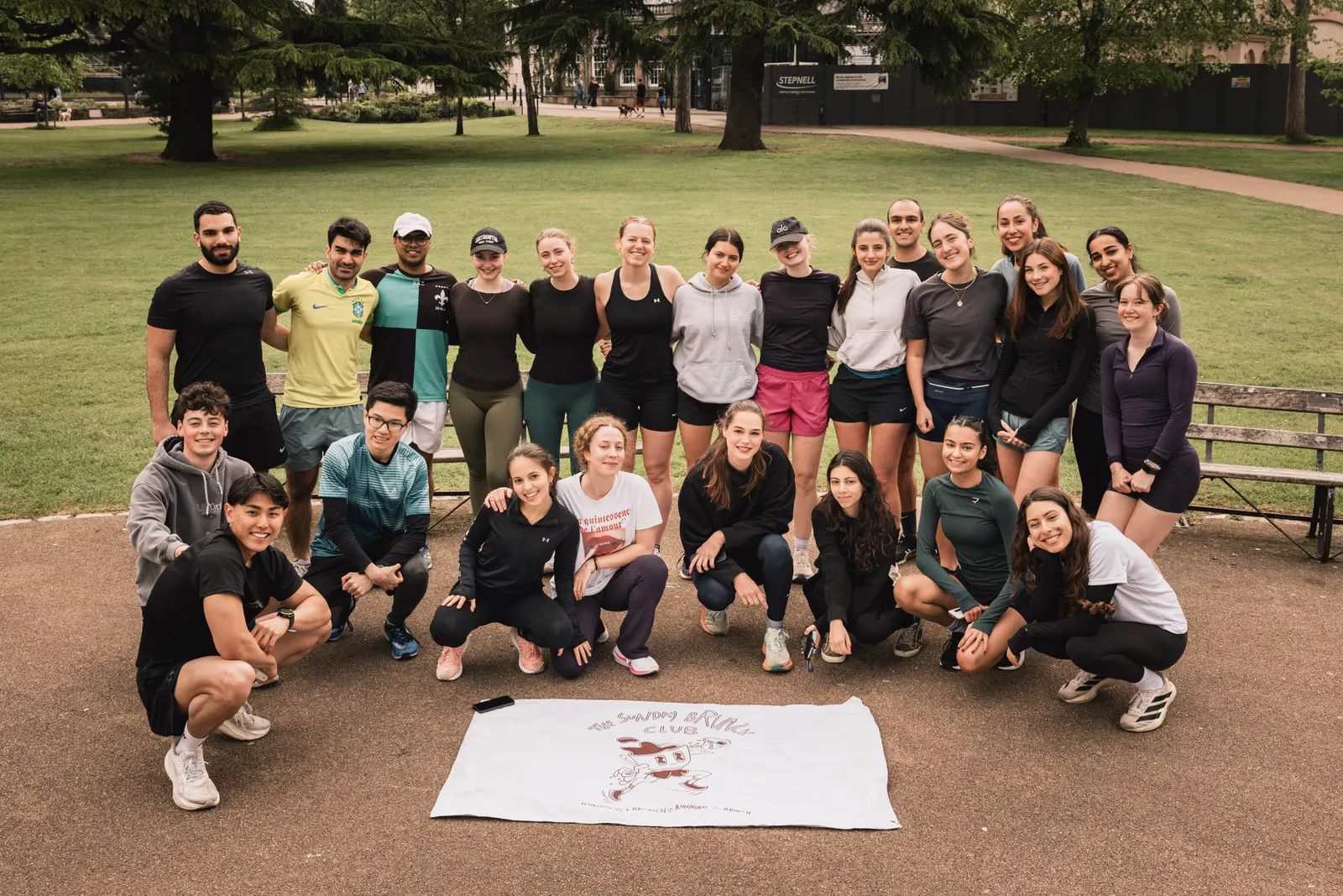 A big group in running kit posing on the grass in a park